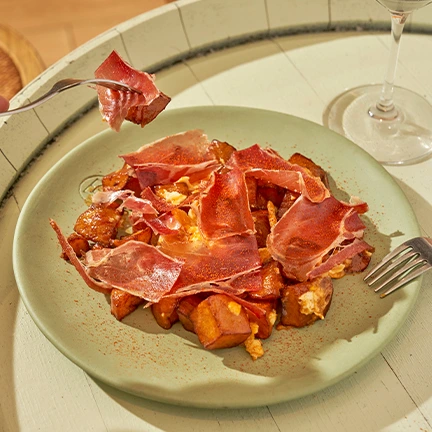 Huevos camperos con patatas fritas, salsa brava y jamón